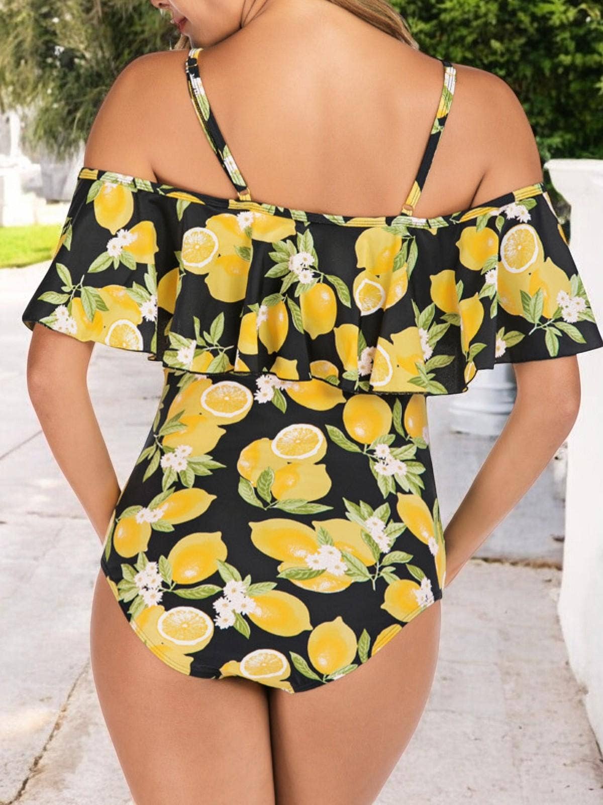 Woman wearing a black swimsuit with yellow lemon print outdoors.