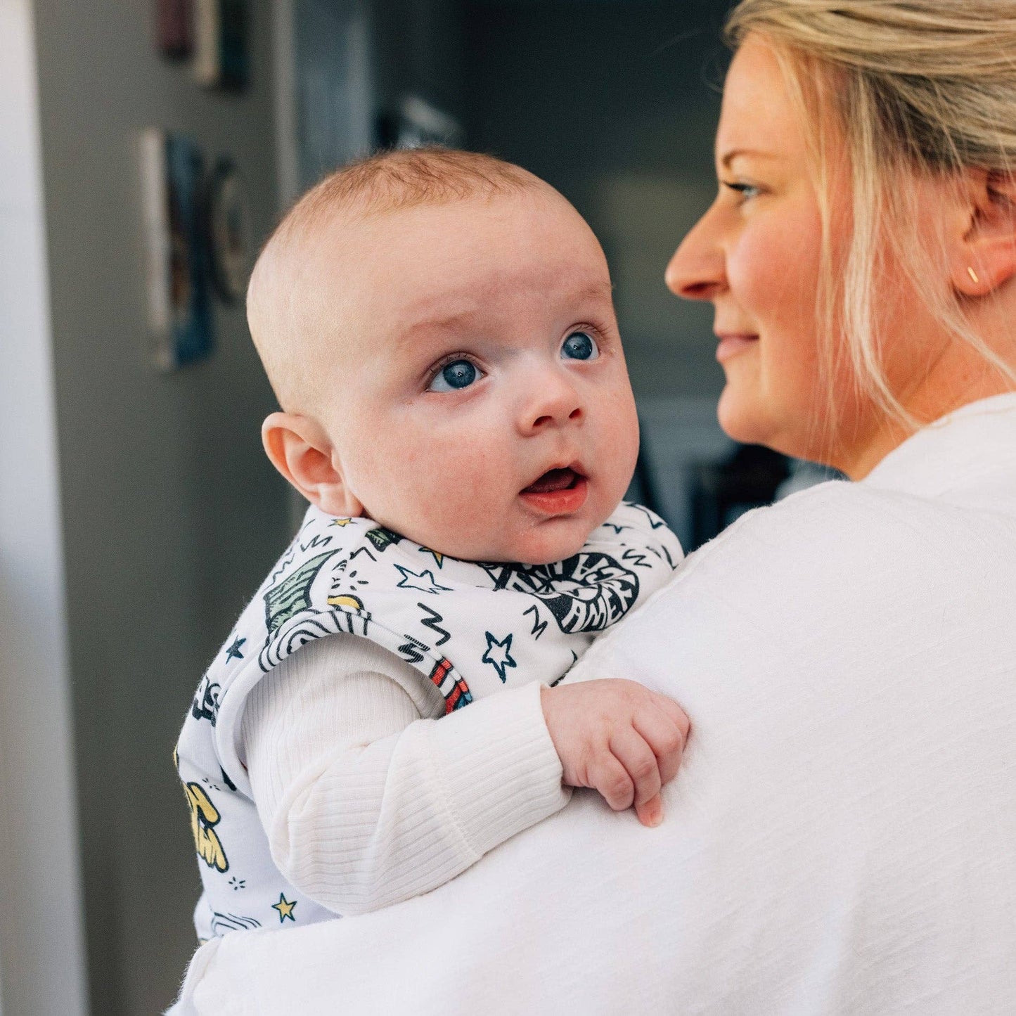 Woman holding a baby wearing a wearable blanket with comic book style Marvel superheroes pattern