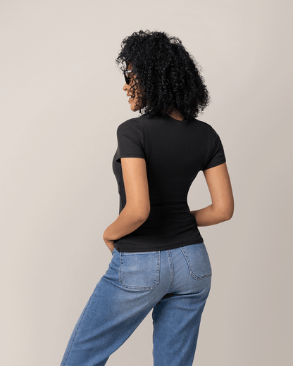 Woman wearing a black t-shirt and blue jeans against a beige background