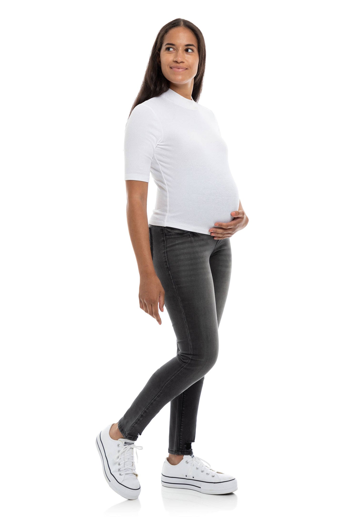 A woman in dark grey, skinny maternity jeans with a bellyband.