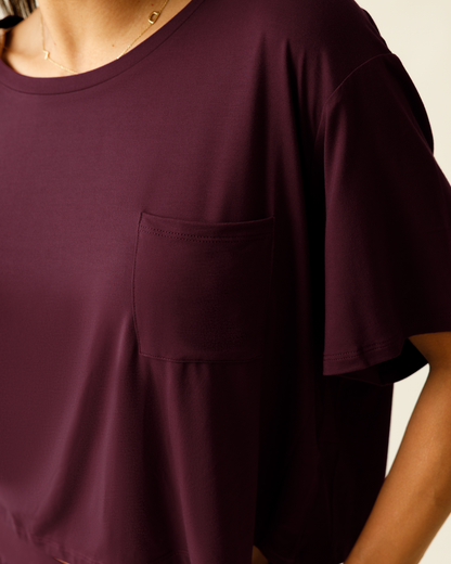 Close-up of a woman wearing a deep burgundy lounge t-shirt with a pocket.