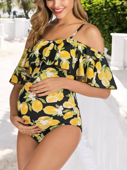 Pregnant woman wearing a black swimsuit with lemon print in an outdoor setting