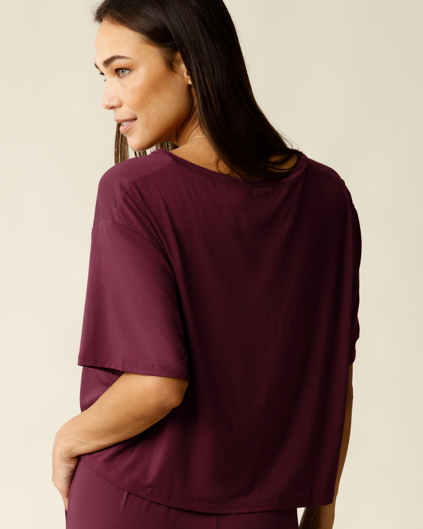 Woman wearing a burgundy top against a beige background