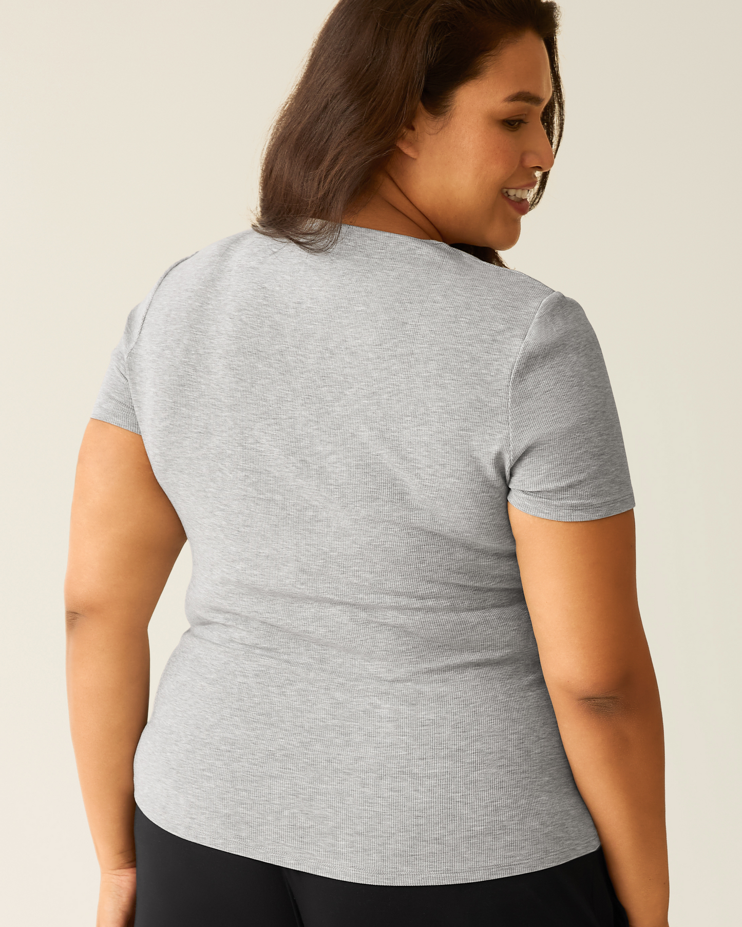 Woman wearing a gray t-shirt against a plain background