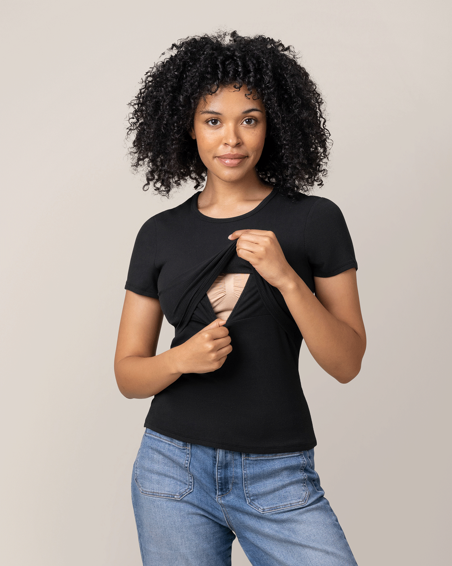 Woman wearing a black t-shirt with breastfeeding access, standing against a plain background