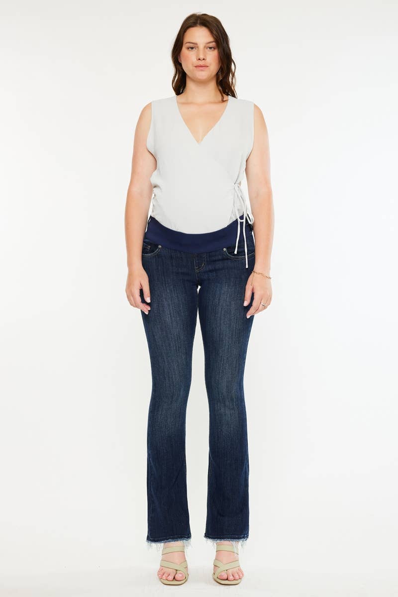Pregnant woman wearing a white sleeveless top and dark blue jeans on a white background