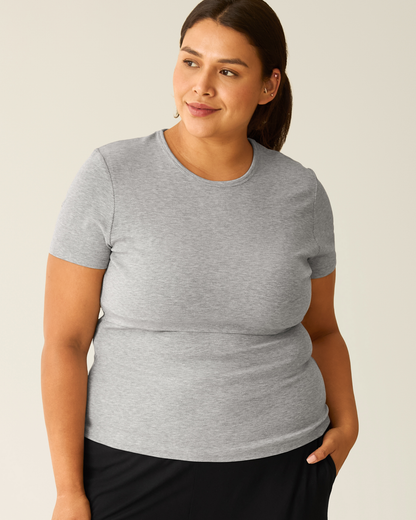 Woman wearing a gray t-shirt with nursing access against a plain background
