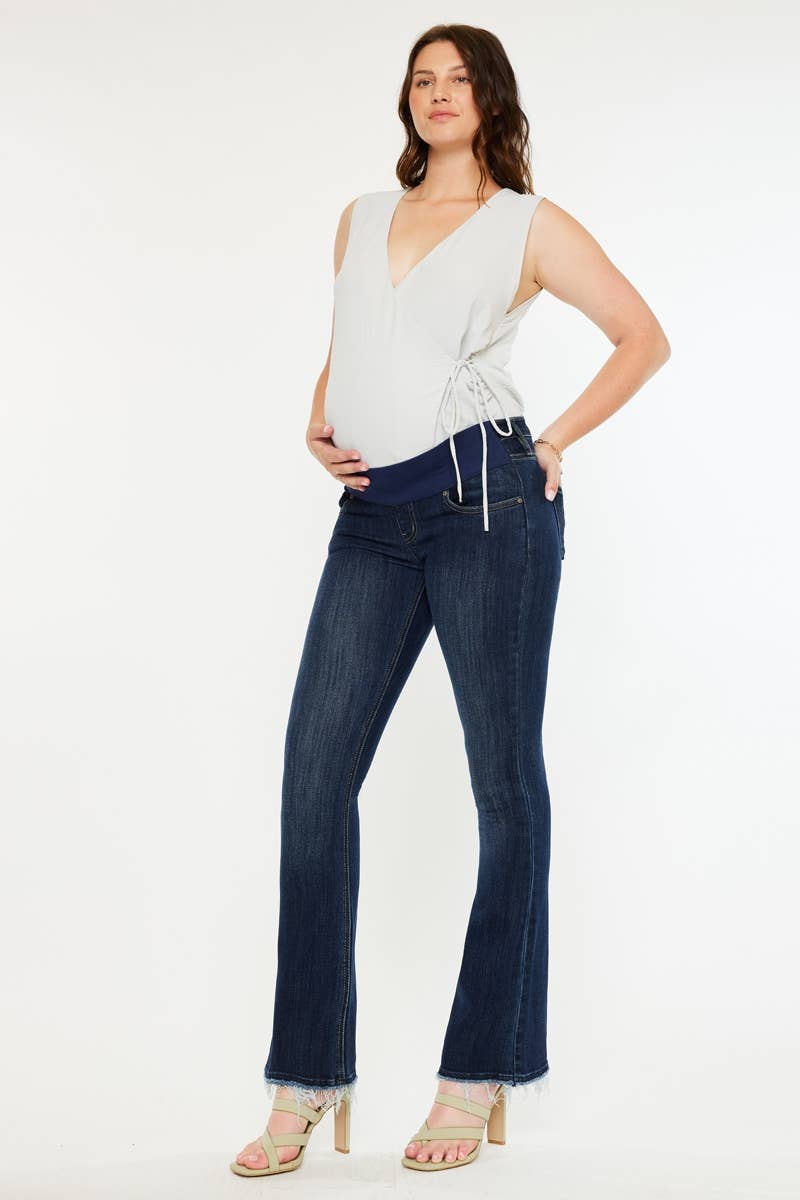 Pregnant woman wearing a white top and dark blue jeans on a white background