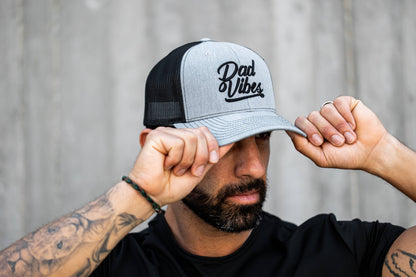 Man wearing a cap with 'Dad Vibes' text against a neutral background