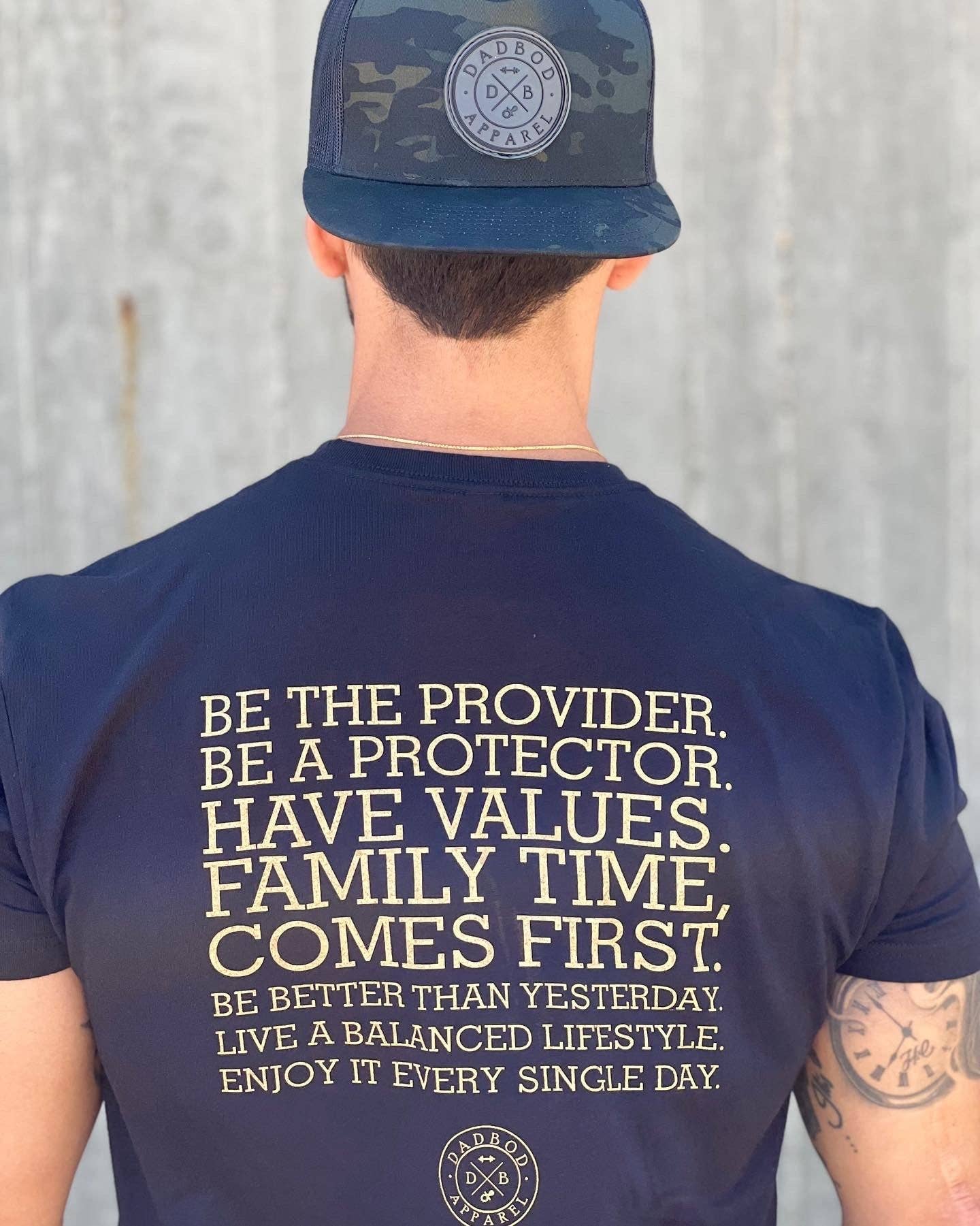 Person wearing a navy t-shirt with motivational text and a cap with a logo on a plain background