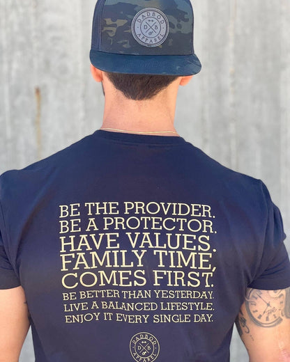 Person wearing a navy t-shirt with motivational text and a cap with a logo on a plain background