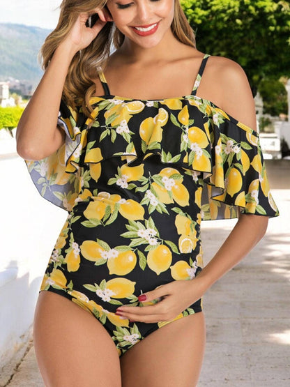 Pregnant woman wearing a black swimsuit with yellow lemon print outdoors.