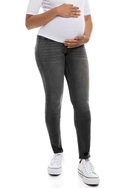 A woman in dark grey, skinny maternity jeans with a bellyband.