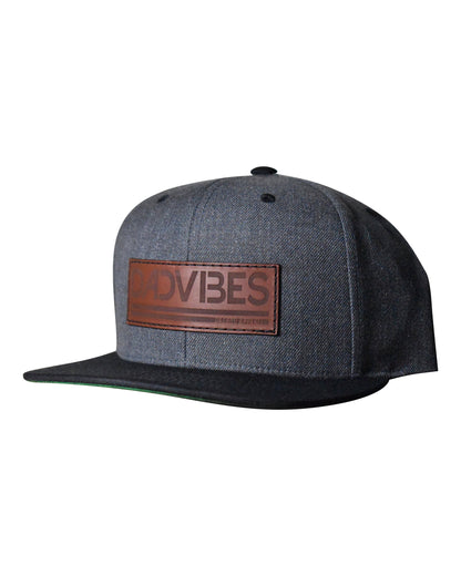 Gray cap with a brown leather patch displaying DADVIBES' on a white background