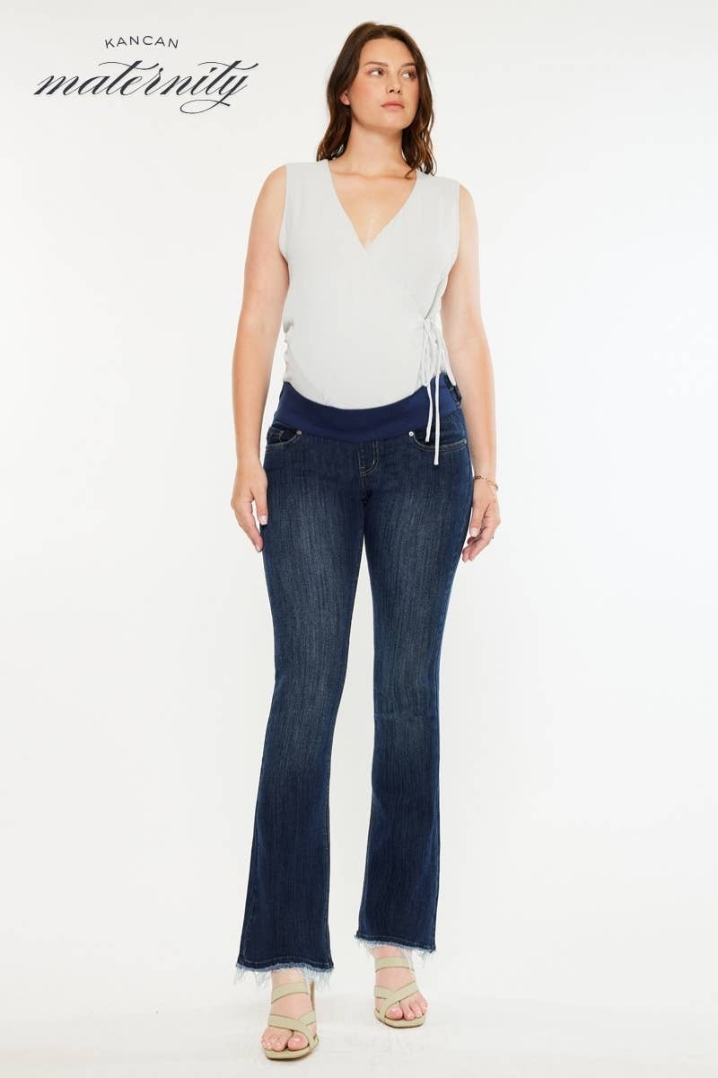 Pregnant woman wearing a white top and dark blue jeans on a white background with 'Kancan Maternity' branding.