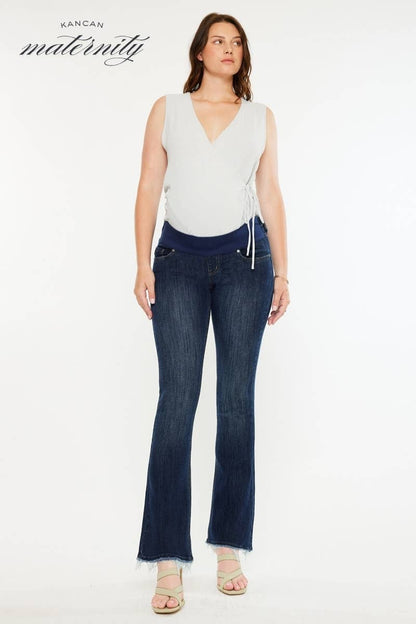 Pregnant woman wearing a white top and dark blue jeans on a white background with 'Kancan Maternity' branding.