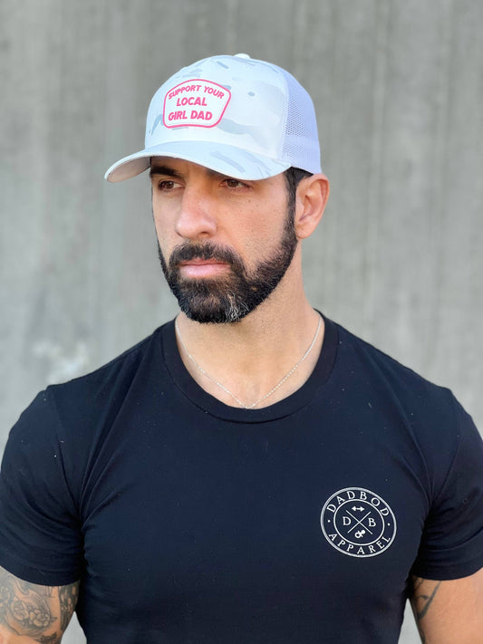 Man wearing a black t-shirt with a logo and a white cap against a gray background