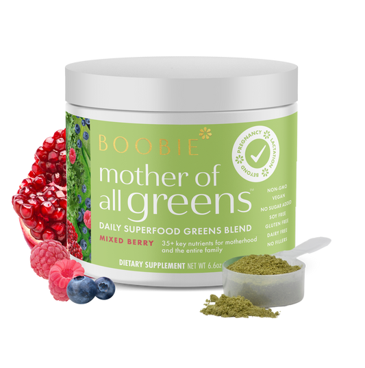 A tub of Boobie Superfoods Mother of All Greens powder in the Mixed Berry flavor with a scoop of the powder and fruits around it.