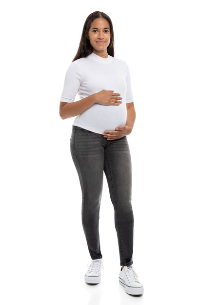 A woman in dark grey, skinny maternity jeans with a bellyband.